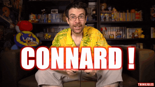 a man in a yellow shirt is sitting on a couch with the words connard written in red