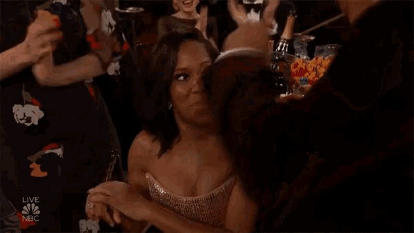 a woman in a strapless dress is talking to a man in a crowd at a live nbc awards show