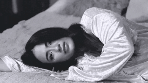a black and white photo of a woman laying on the floor