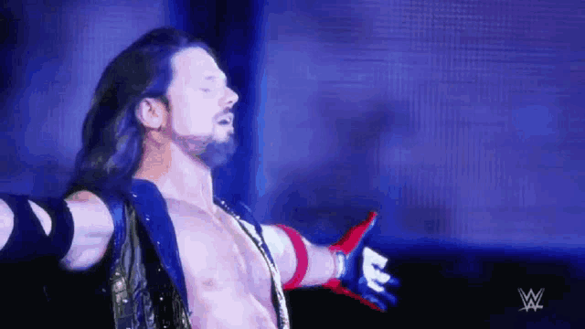 a shirtless wrestler with his arms outstretched in front of a wwe logo