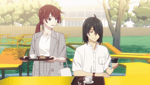 a man and a woman are sitting at a table and the woman is holding a tray