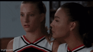 two cheerleaders are standing next to each other and looking at each other with their eyes closed .