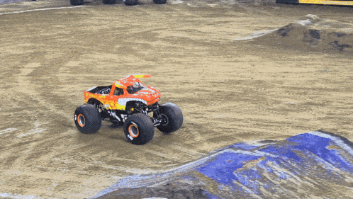 a monster truck is driving on a dirt track with a sign behind it that says ' monster jam ' on it