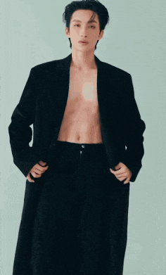 a man without a shirt is wearing a black jacket and pants .