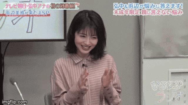a woman in a striped shirt is clapping her hands in front of a sign that says ' imgflip.com ' on it