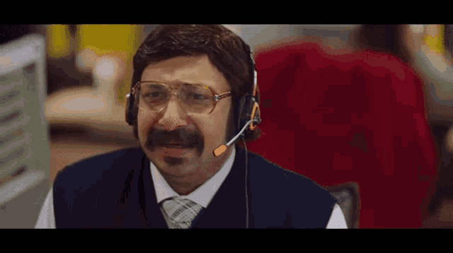 a man with a mustache and glasses wearing a headset