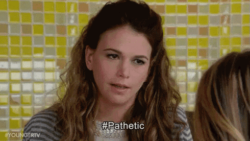 a woman is sitting at a table talking to another woman while wearing a striped shirt and a necklace .