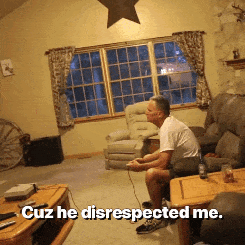 a man sits on a couch playing a video game with the words cuz he disrespected me below him