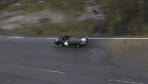 two sports cars are racing down a wet road .