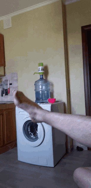 a person 's foot is on a washing machine in a kitchen