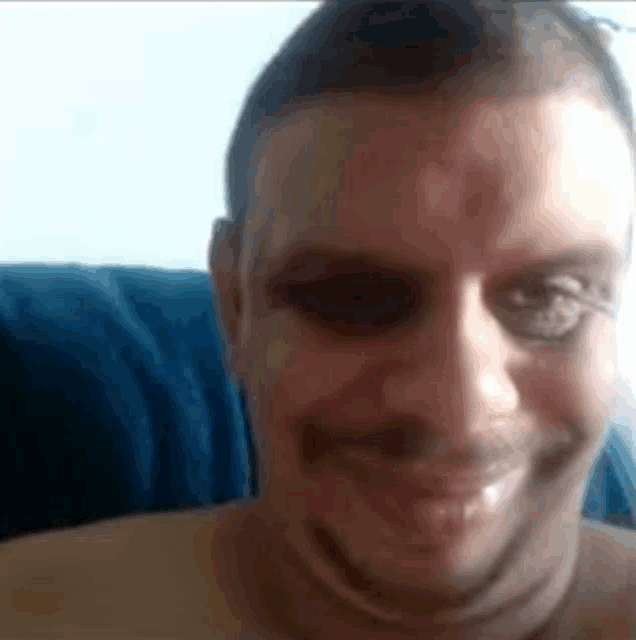 a man without a shirt is smiling and looking at the camera .