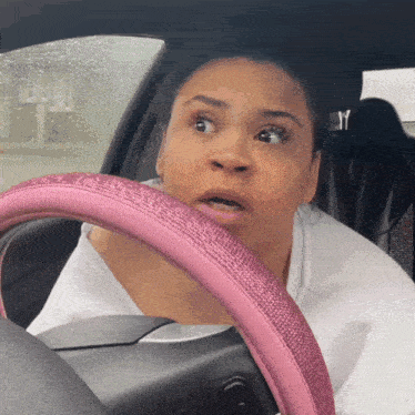 a woman with a pink steering wheel looks surprised