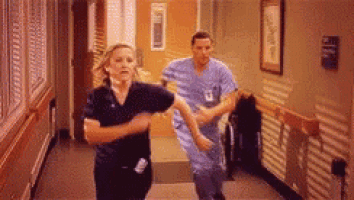a man and a woman are running down a hospital hallway