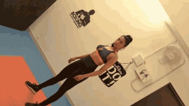 a woman standing next to a punching bag that says " do it "
