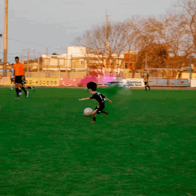 a boy kicking a soccer ball on a field with a sign that says 32-430555 on it