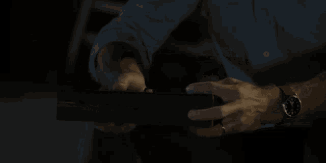 a man wearing a watch and a ring is opening a box