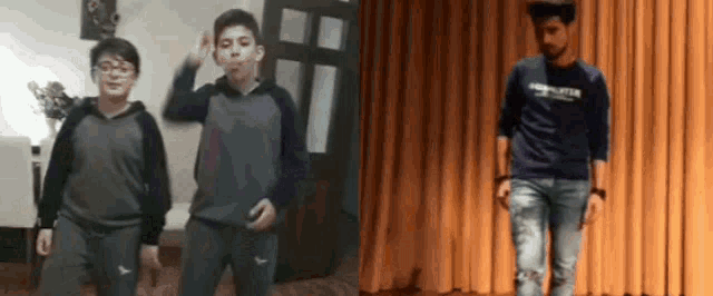 two boys are dancing in a living room and a man is standing on a stage .
