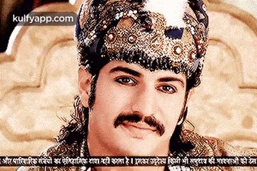 a man with a mustache is wearing a crown and a turban .