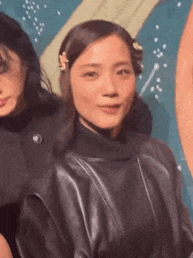a woman in a black leather jacket is standing next to another woman in a black jacket .