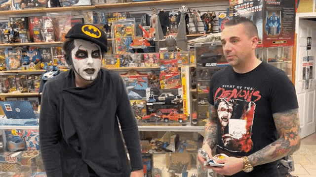 a man wearing a night of the demons shirt is standing next to another man