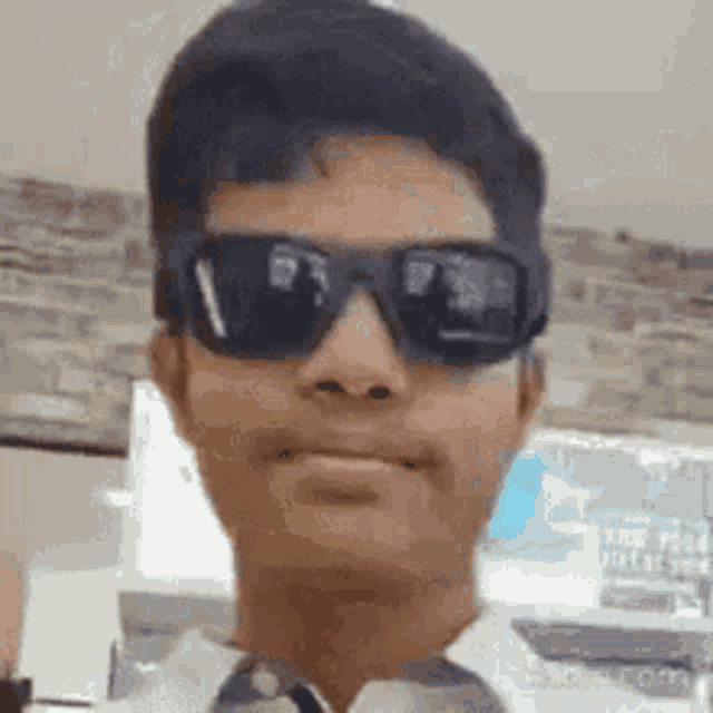 a young man wearing sunglasses and a white shirt is making a funny face .