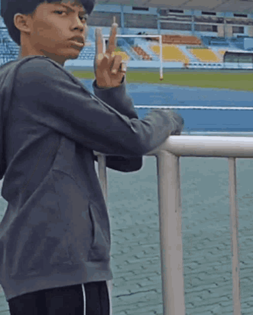 a young man giving the middle finger while leaning against a railing