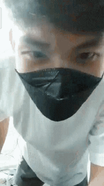 a man wearing a black face mask and a white shirt .