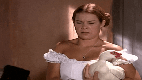 a woman in a white dress holds a white chicken