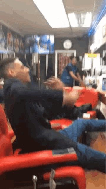 a man in a suit is sitting in a red chair in a barber shop