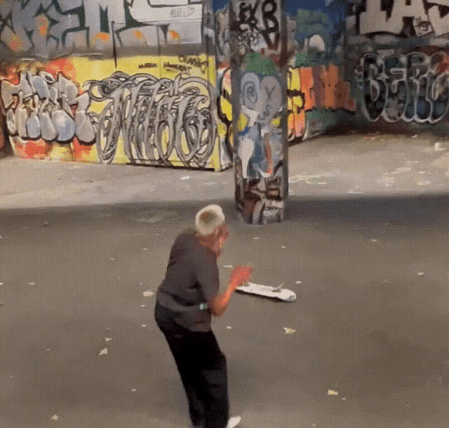 a man playing skateboard in front of a wall with graffiti on it that says ' a '