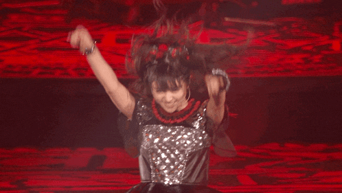 a girl is dancing on a stage with a red background