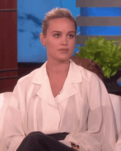 a woman wearing a white shirt and black pants is sitting on a couch