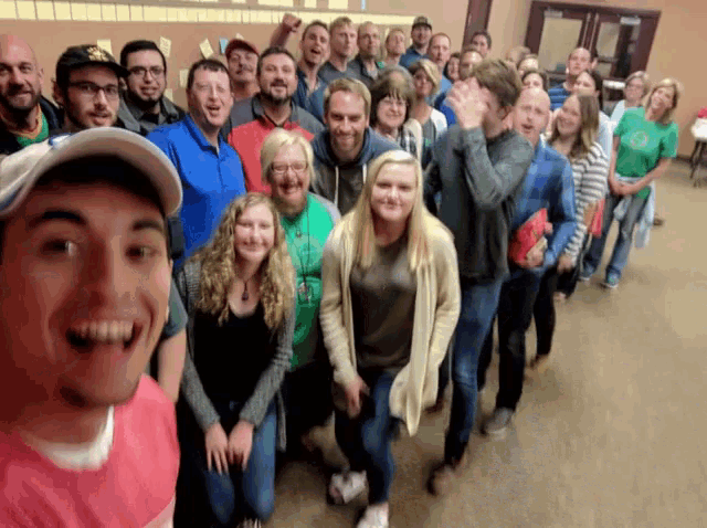 a group of people are posing for a photo and one of them is wearing a pink shirt