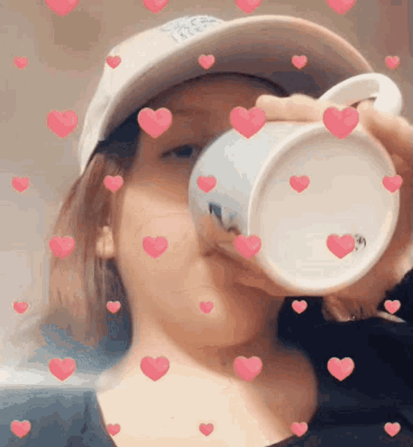 a woman wearing a hat is drinking from a cup with hearts around her