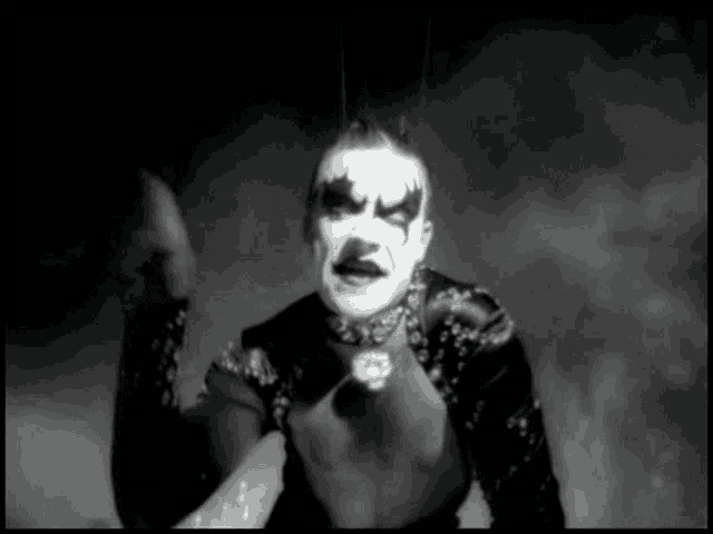 a black and white photo of a man with makeup on his face and a choker .