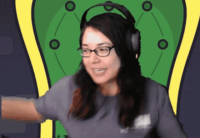 a woman wearing headphones and glasses is dancing in front of a green background