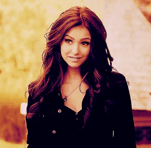 a woman wearing a black shirt and a necklace is smiling .