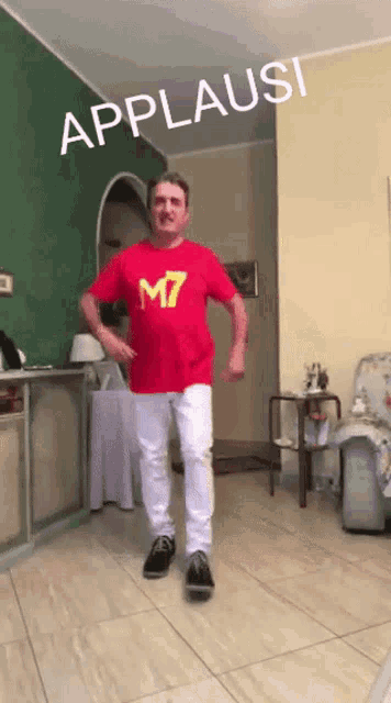 a man wearing a red shirt with the number m7 on it is dancing in a living room