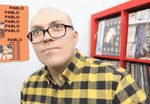 a man wearing glasses stands in front of a poster that says pablo on it