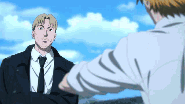 a man in a suit and tie talking to another man in a white shirt