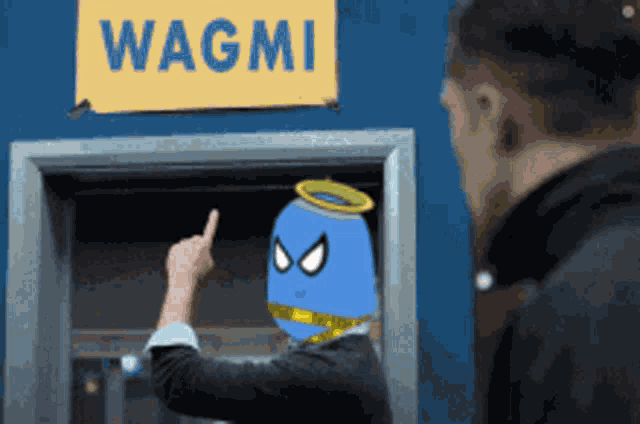 a man points to a sign that says wagmi on it