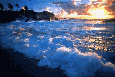 a sunset over a body of water with waves crashing on the shore