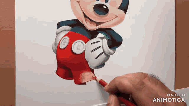 a person is drawing a picture of mickey mouse on a piece of paper