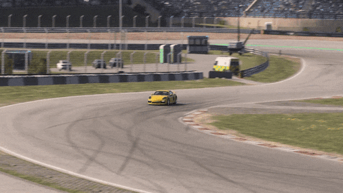 a yellow race car is going around a curve on a race track