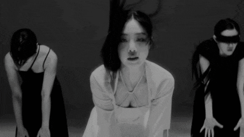 a black and white photo of three women dancing in a dark room