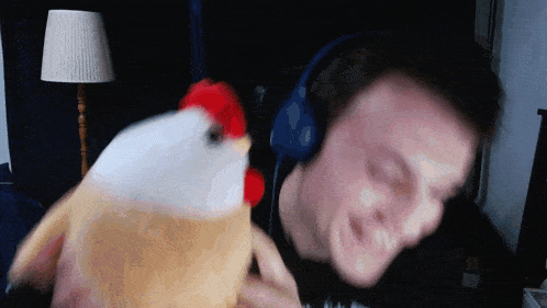 a man wearing headphones holds a stuffed chicken in his hands
