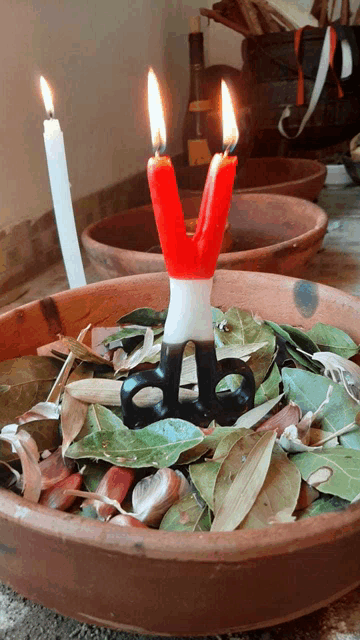 a bowl of leaves and a pair of scissors with two candles in it