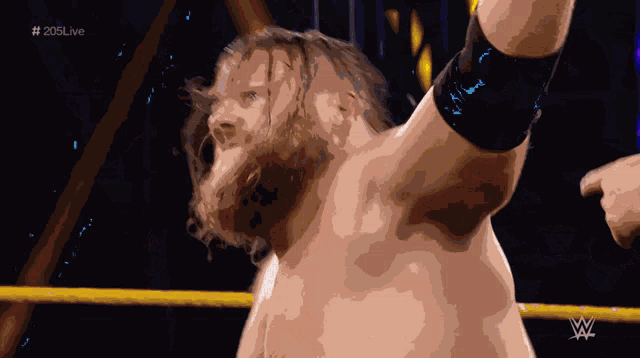 a man with a beard is in a wrestling ring with # 205live on the bottom