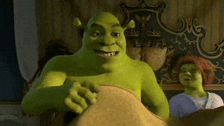 shrek is sitting on a bed next to a woman in a room .