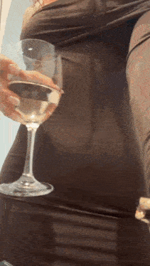 a woman is holding a glass of wine in her hand .